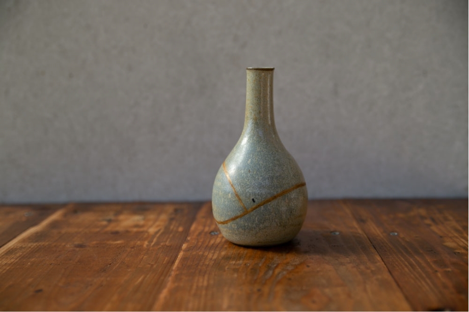 木の床に置かれた一輪挿しの陶器