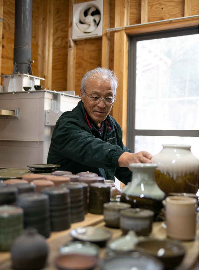 陶芸作品に手を伸ばす陶芸家